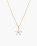 Collar Fleur, colgante de flor de cinco pétalos con piedras transparentes en talla marquesa en cadena de eslabones en tono dorado, sobre fondo blanco
