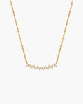 Collar Aria en blanco, barra curva en tono dorado con una fila de piedras redondas transparentes, en cadena de eslabones