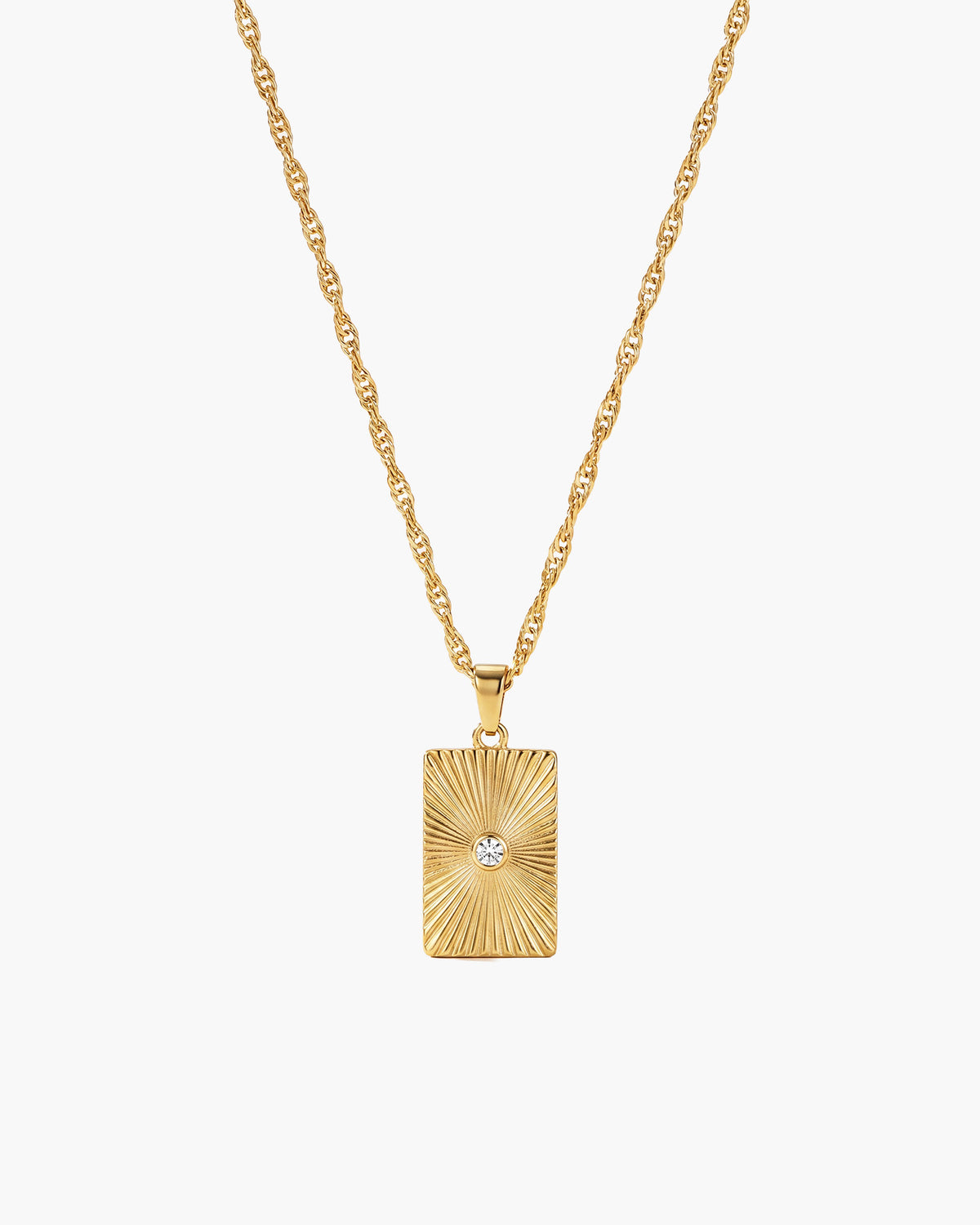Collar Celeste, colgante rectangular en tono dorado con relieve de rayos de sol y una piedra transparente en el centro
