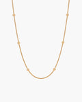 Collar Bella, cadena snake fina en tono dorado con cuentas doradas pulidas a intervalos regulares, sobre fondo blanco