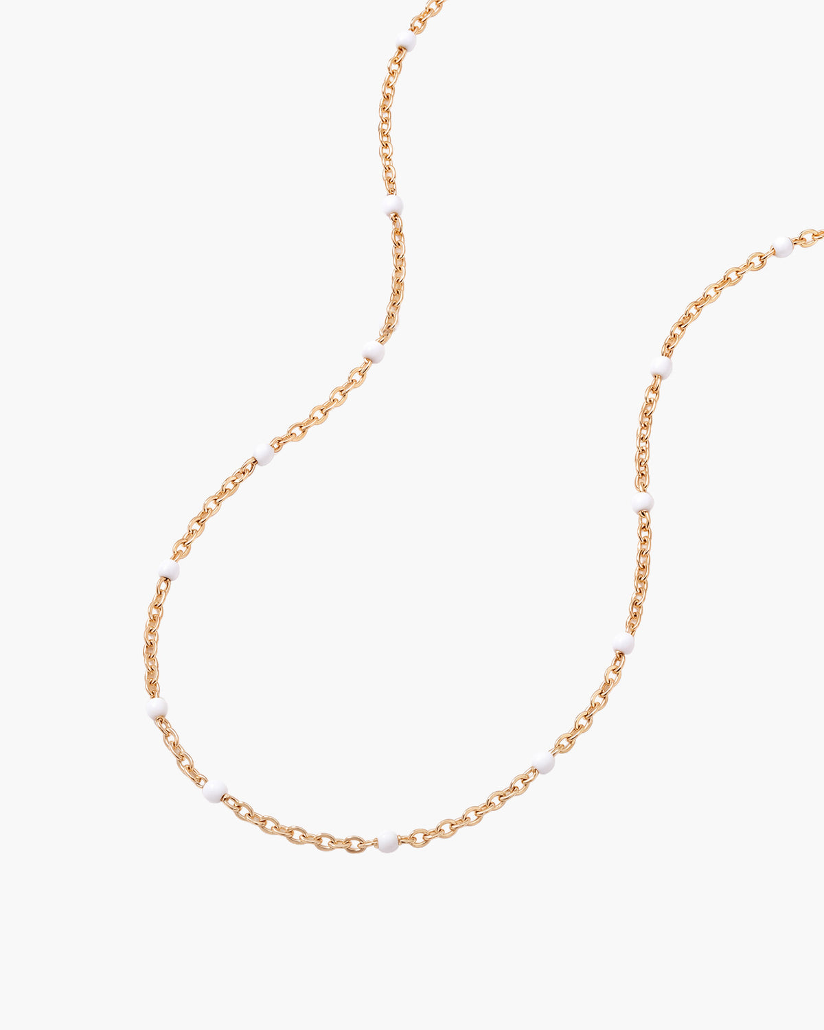 Collar Dot, cadena de eslabones en tono dorado con pequeños puntos de esmalte blanco repartidos a lo largo, sobre fondo blanco