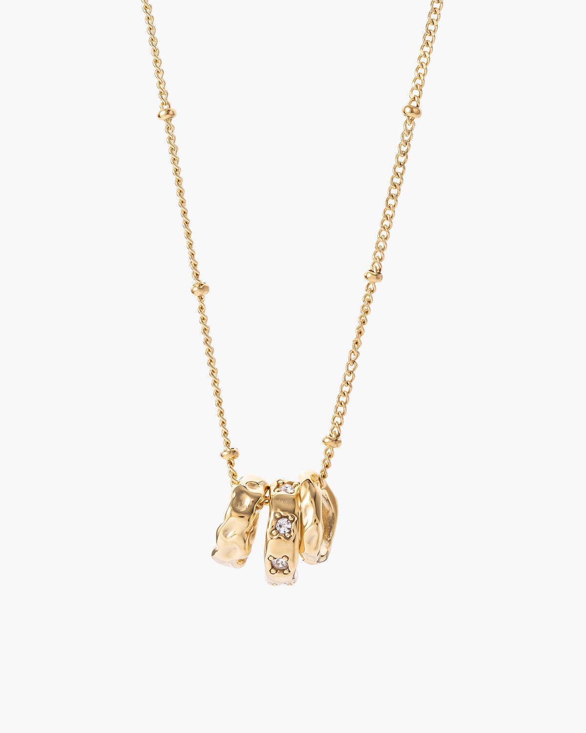 Collar Vera, tres aros colgantes en tono dorado, uno martillado y otro con piedras transparentes, en cadena de bolitas
